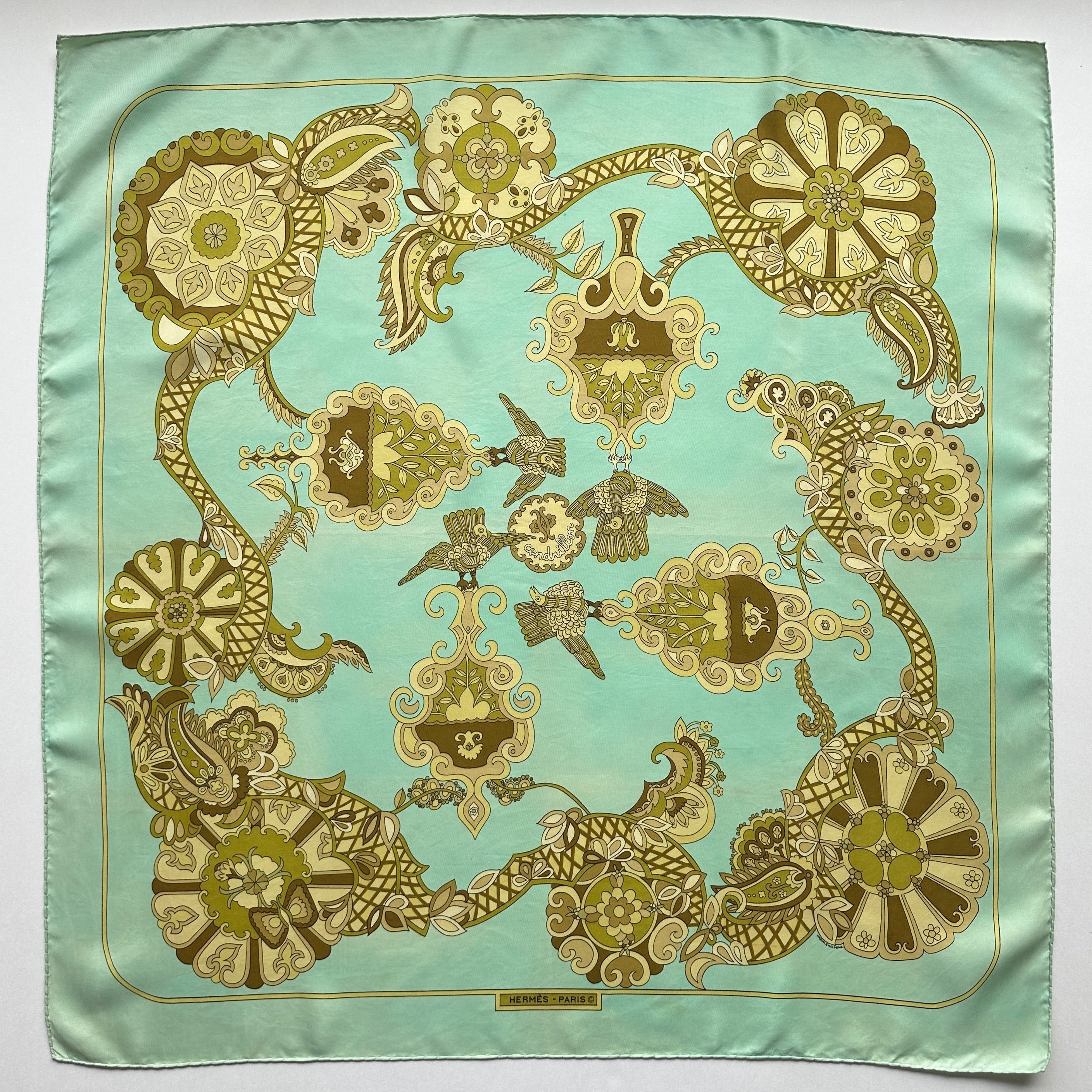 Carré Hermès vintage "Cendrillon" (1972) déployé, fond vert menthe avec motifs géométriques olive et or typiques des années 70.