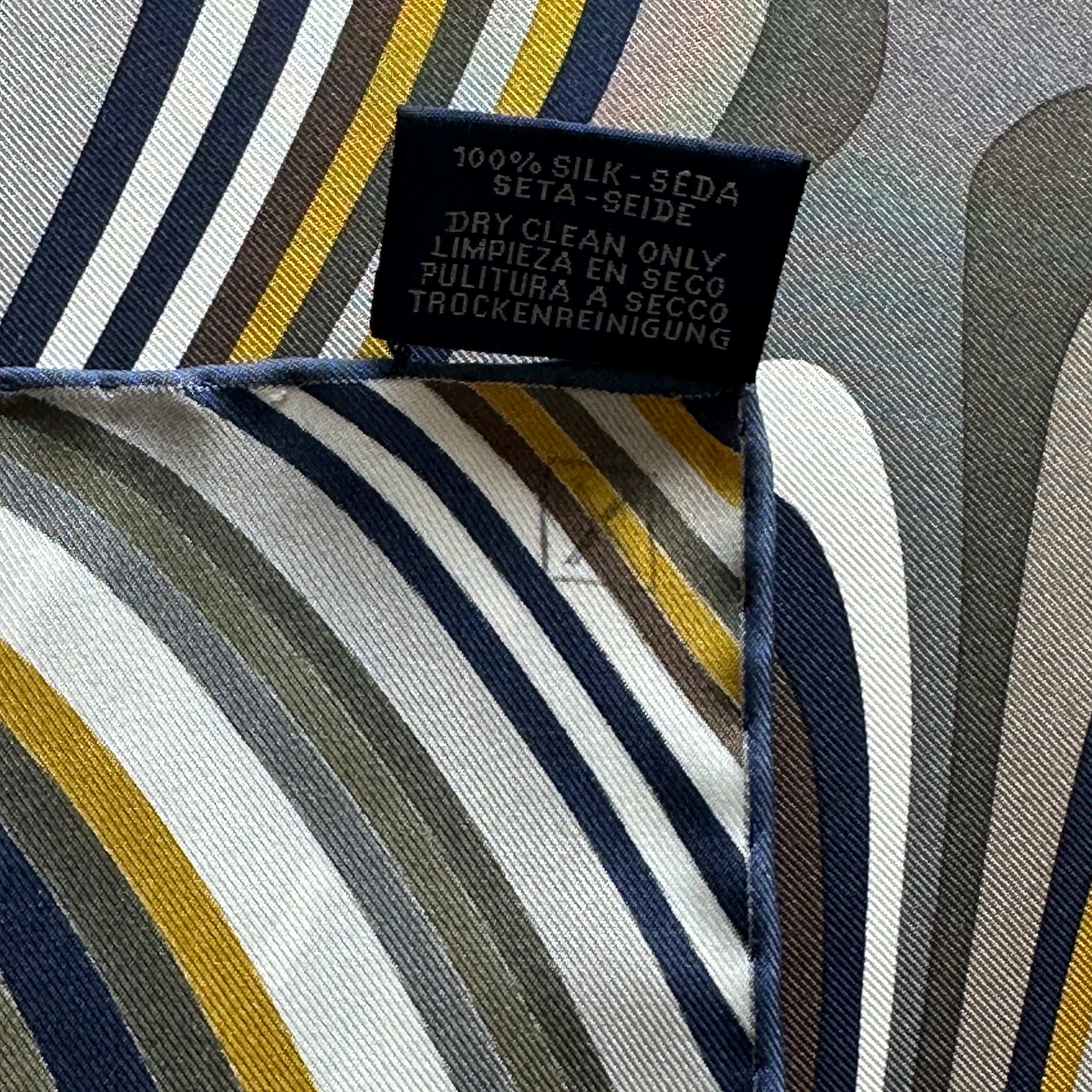 erso de l'étiquette d'entretien noire (Dry Clean Only) sur fond de motif rayé gris et ocre.