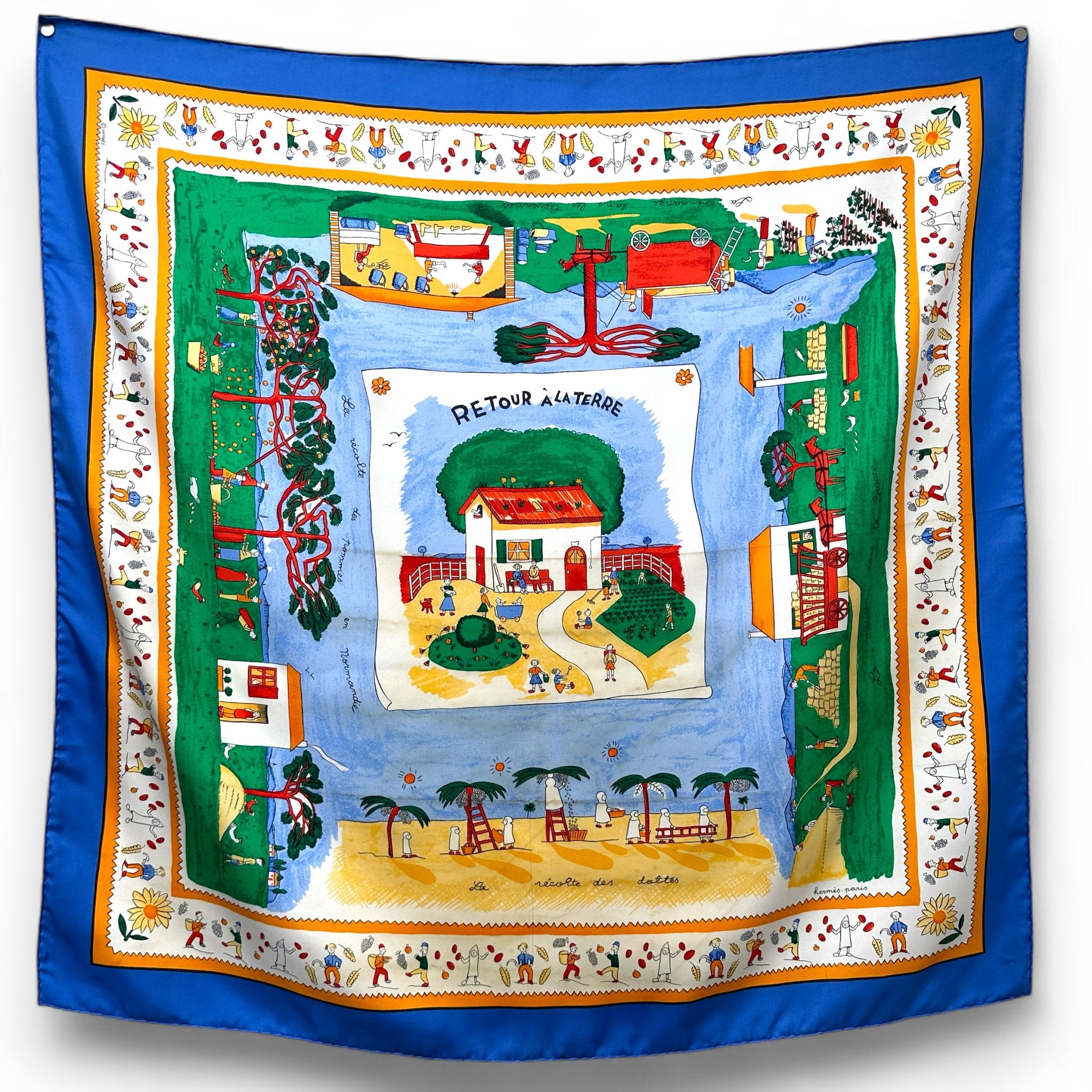 foulard carré en soir intitulé retour à la terre representant une maison au centre avec des paysages de campagne couleurs dominantes bleu blanc vert