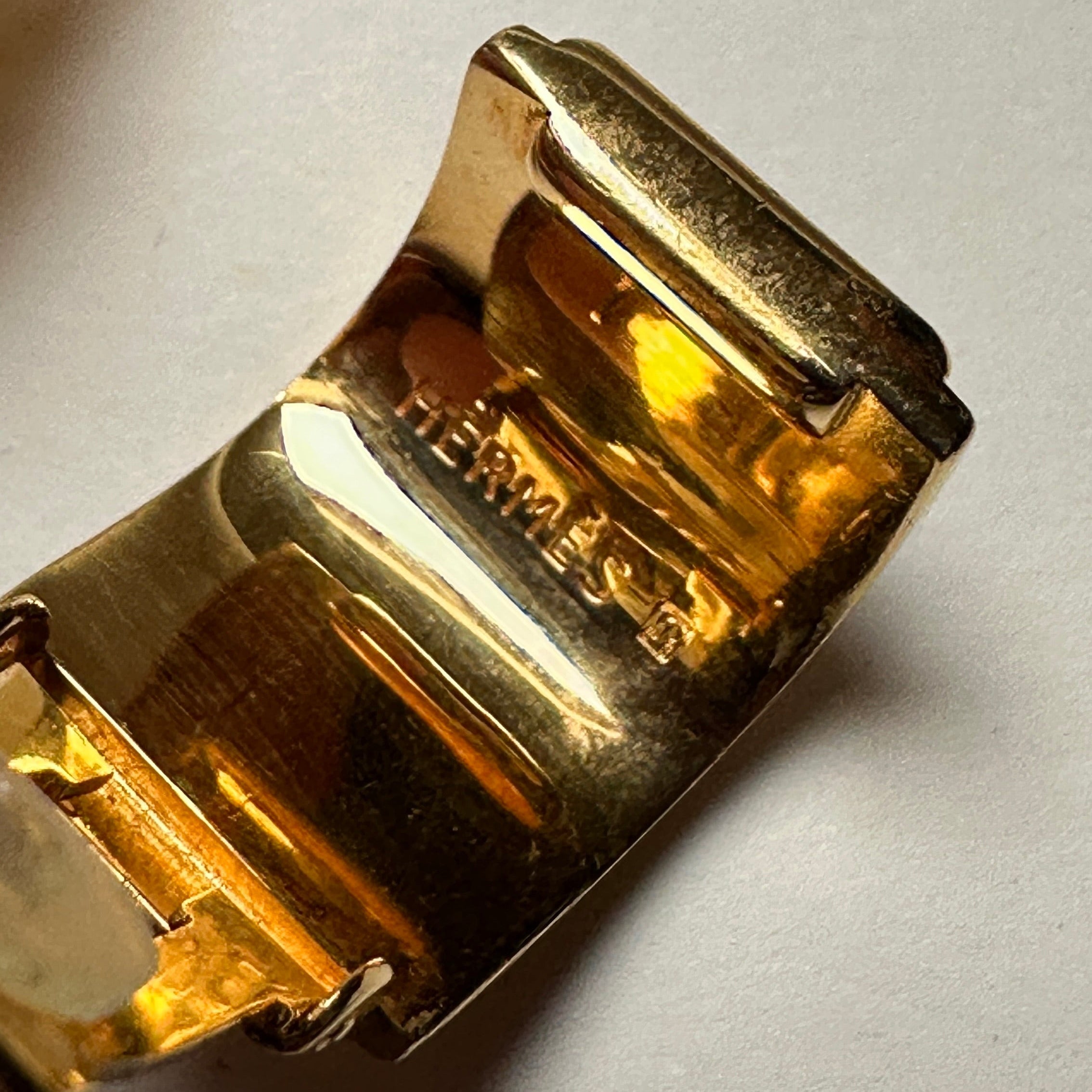 Vue arrière des boucles d'oreilles montrant l'état de la dorure, le mécanisme des clips avec patins, et la gravure de la signature HERMÈS PARIS.